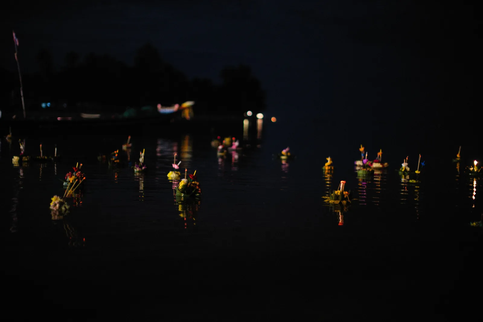 Decorated candle floats being released onto a river at night during Loi Krathong in Thailand
