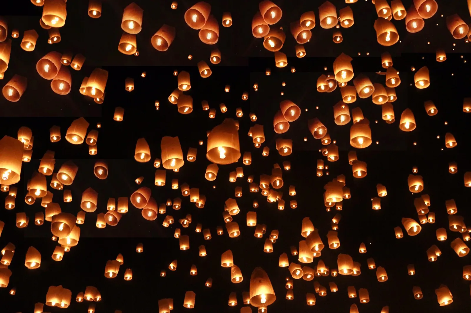 Paper lanterns rising into the night sky during the Yi Peng festival in northern Thailand