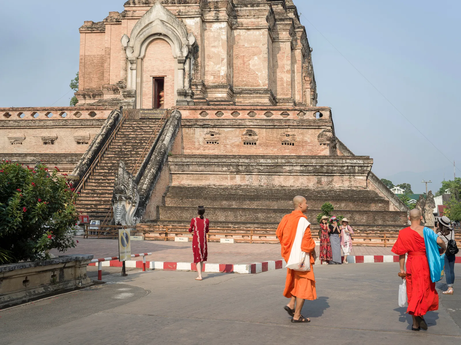 Novice monks in orange robes walking past a temple entrance in Chiang Mai's old city