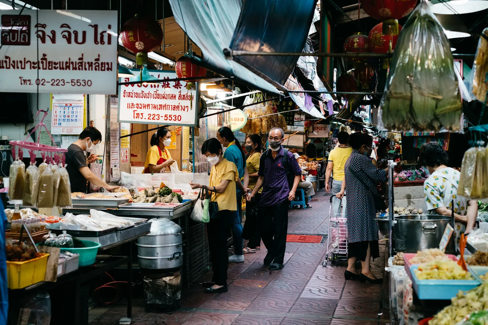 Vendors and shoppers in a busy covered fresh market lane in Thailand, where cooking classes buy their ingredients
