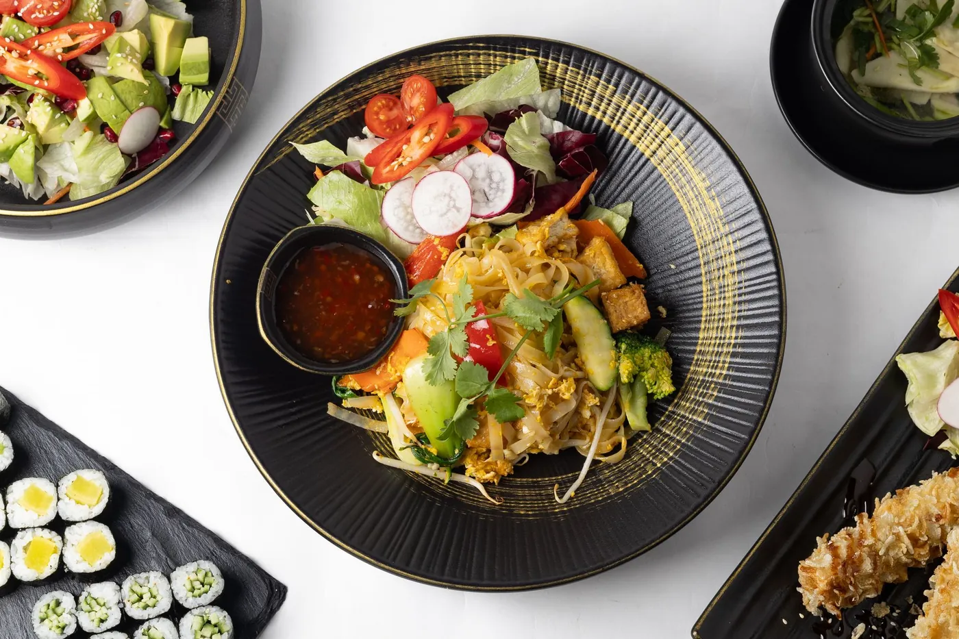 A vegetarian noodle dish with tofu, broccoli and mixed vegetables served with a chilli dipping sauce on the side