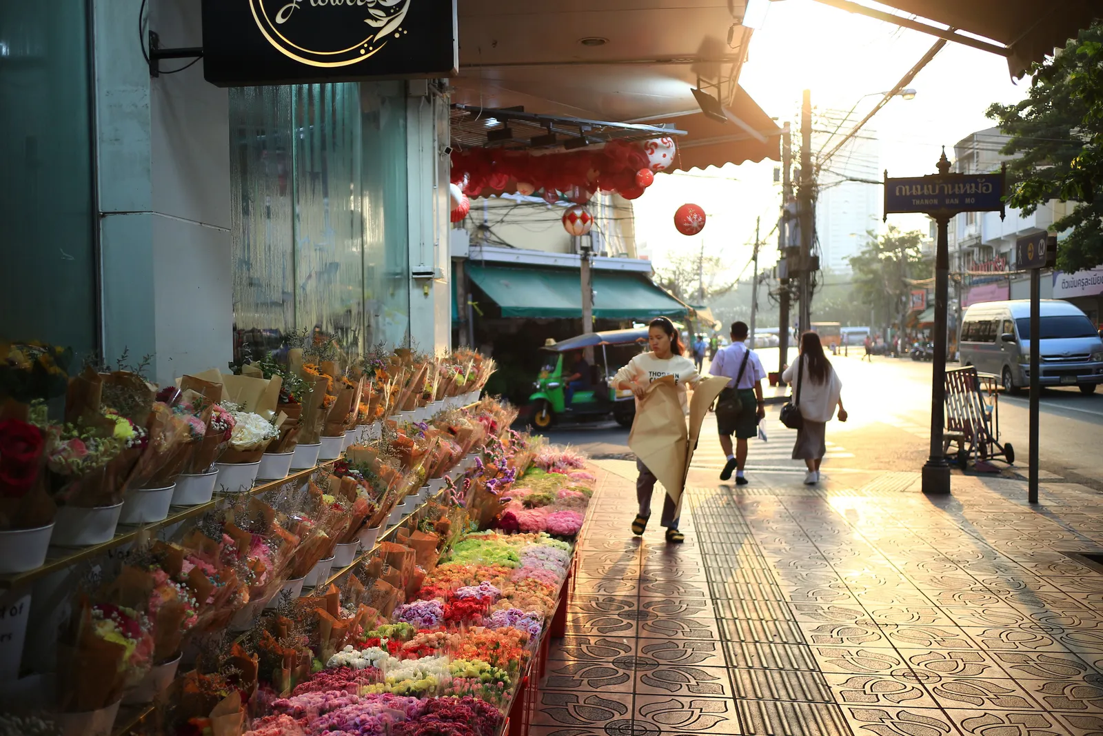 A busy daytime street scene in a Bangkok shopping district with pedestrians and shopfronts