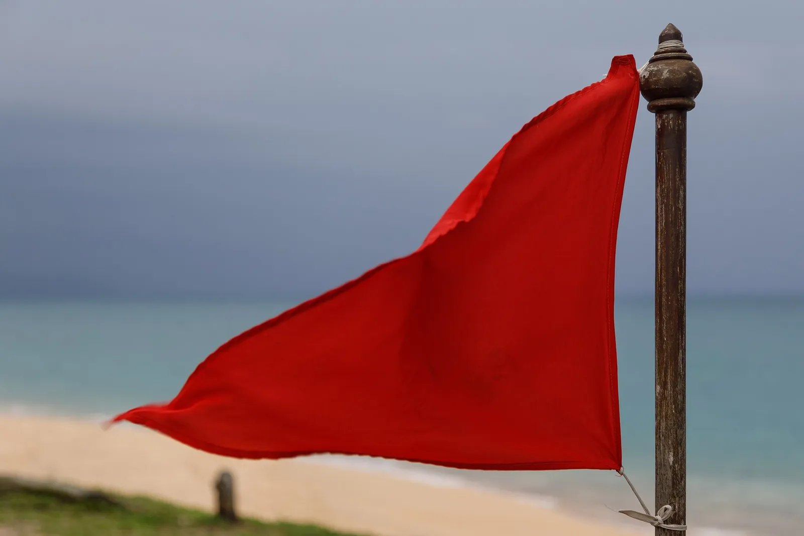 A warning flag planted in the sand at Mai Khao Beach in Phuket, Thailand