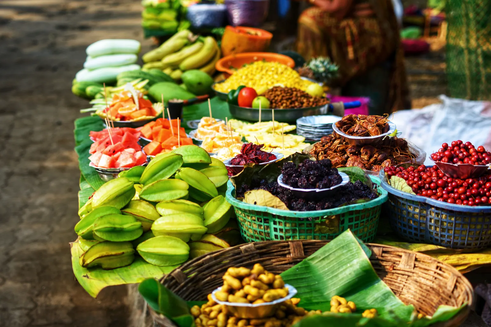 A Thai market stall displaying tropical fruit and vegetables laid out on banana leaves