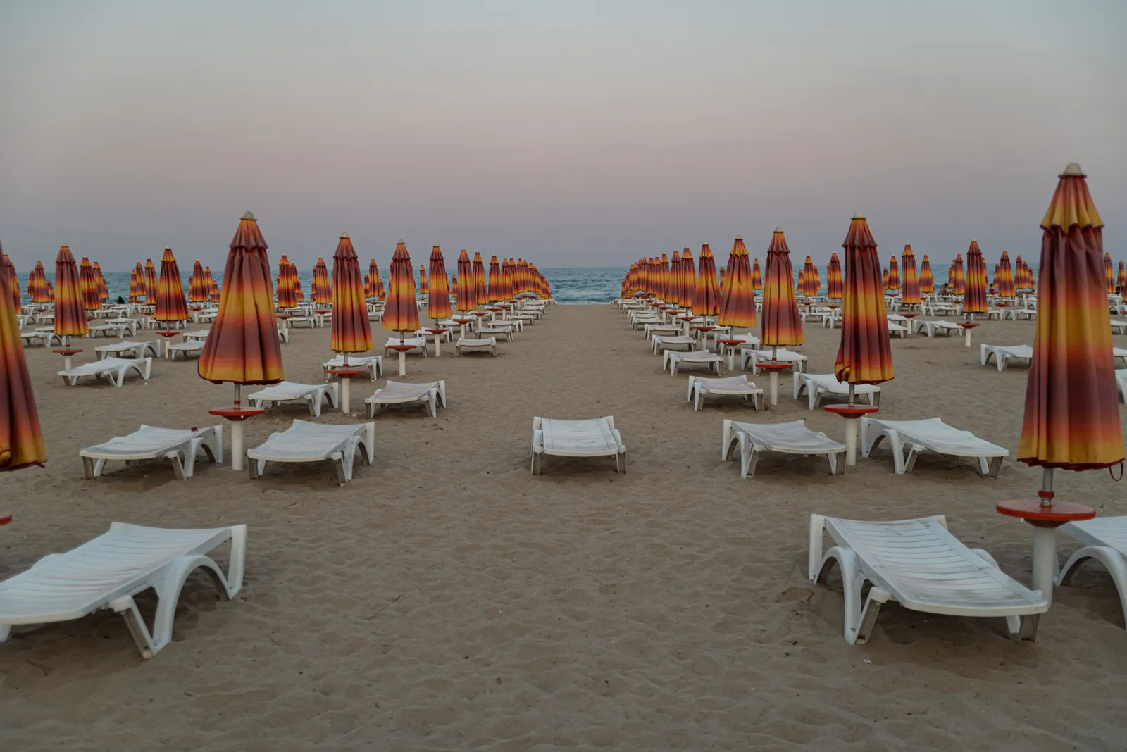 Two sun loungers facing a calm sea at sunset on a quiet Thai beach