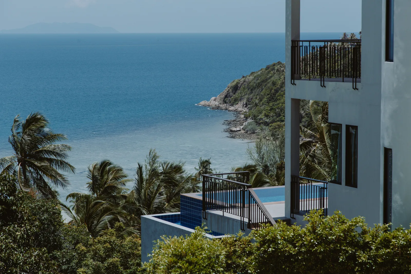 A private villa terrace with a small plunge pool among tropical palms overlooking a bay