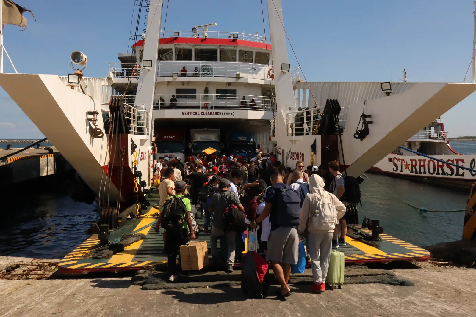 passengers with luggage boarding a ferry at a pier in southern Thailand in daylight
