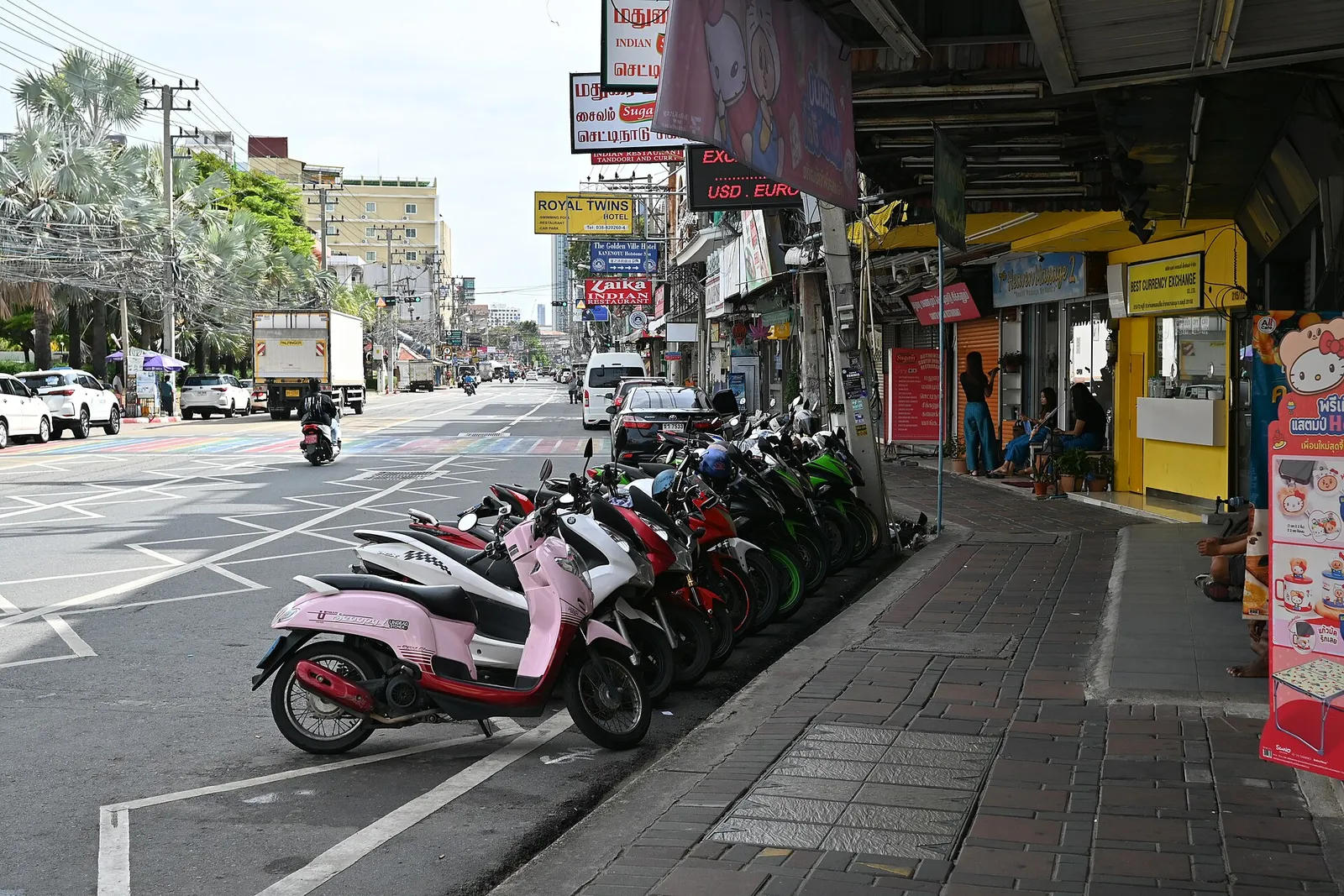 Parked motorbikes and shopfronts along a street in Thailand