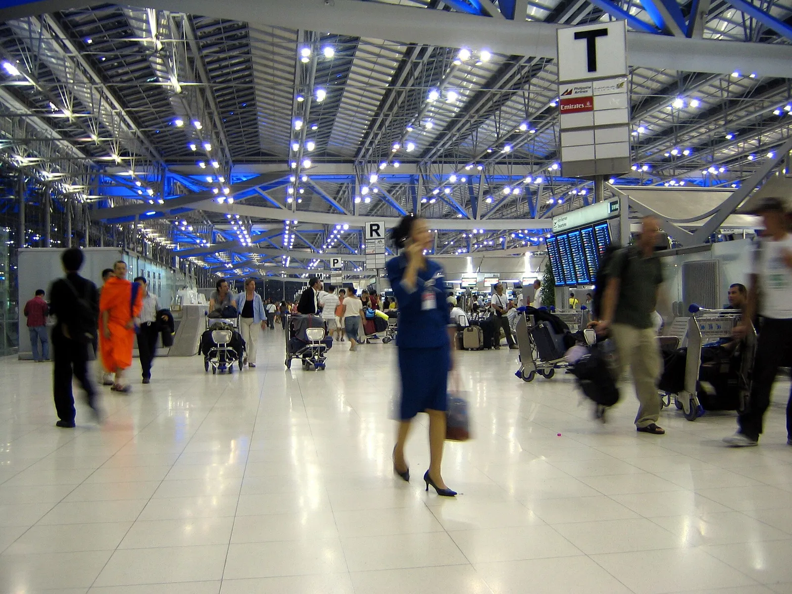 Travellers with luggage inside the bright modern terminal of Suvarnabhumi Airport in Bangkok, Thailand